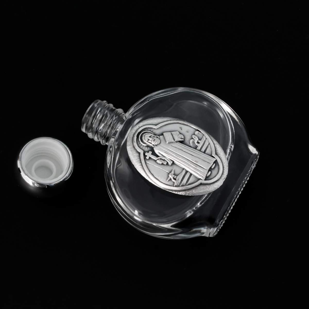 Glass holy water bottle with a metal embossed plaque of Saint Benedict on the front. Plastic screw on cap that is a shiny silver tone color.