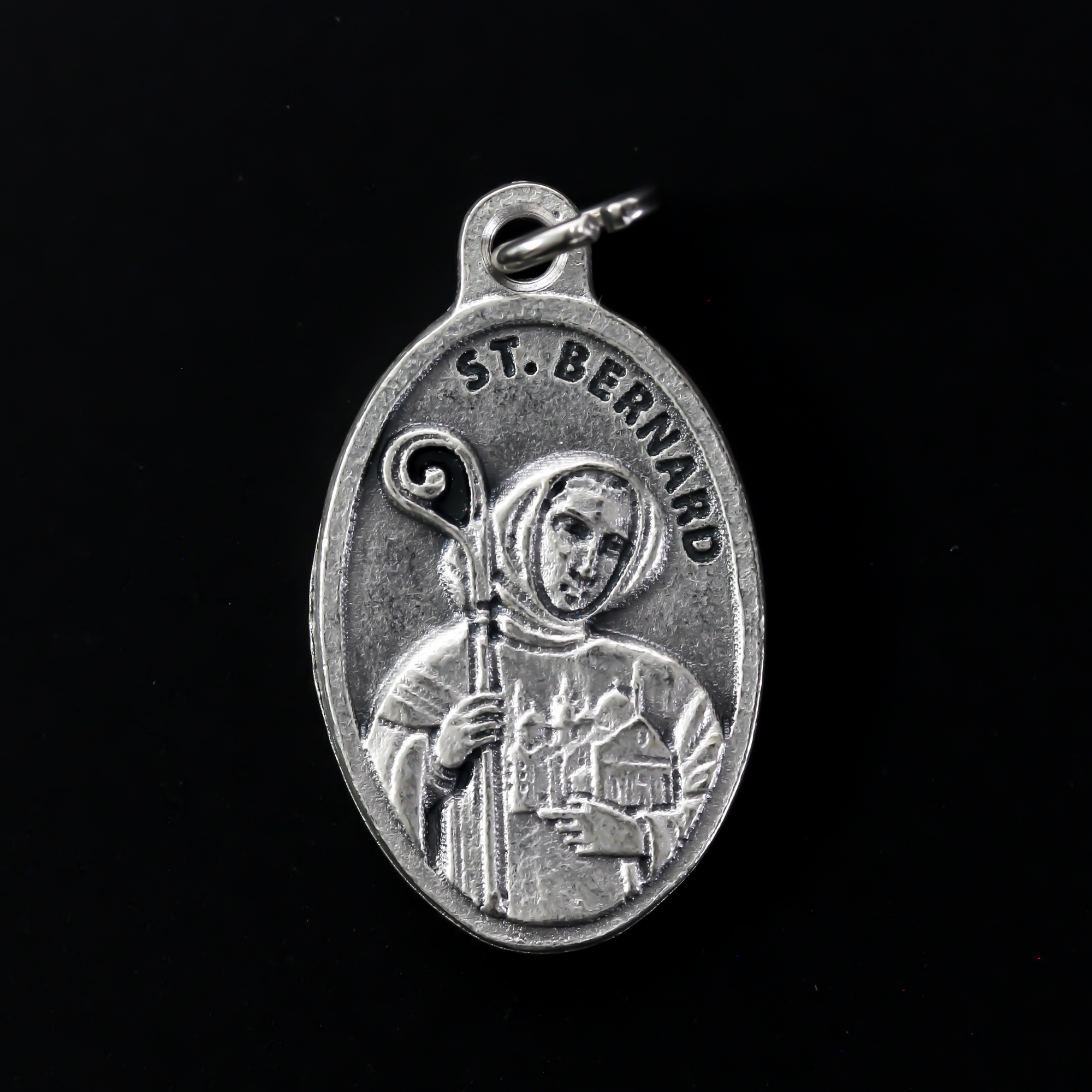 Saint Bernard of Clairvaux medal that depicts the saint on the front holding a church and crozier. Marked "Pray For Us" on the back