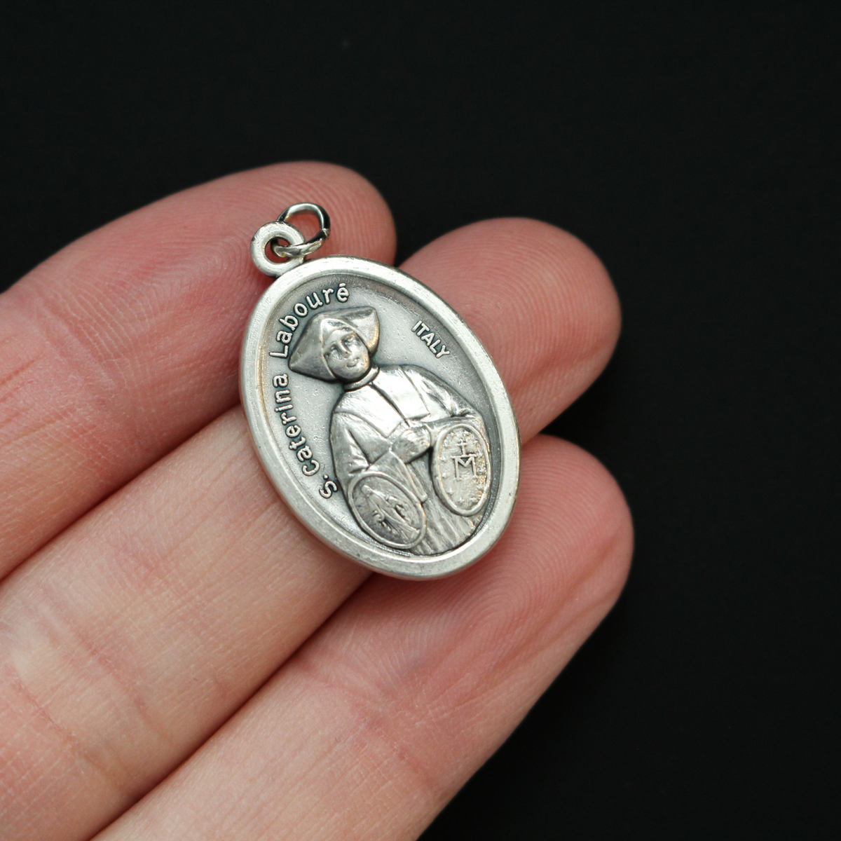 Saint Catherine Labouré medal that depicts the saint on the front with the Miraculous Medal and the reverse is marked "Pray For Us