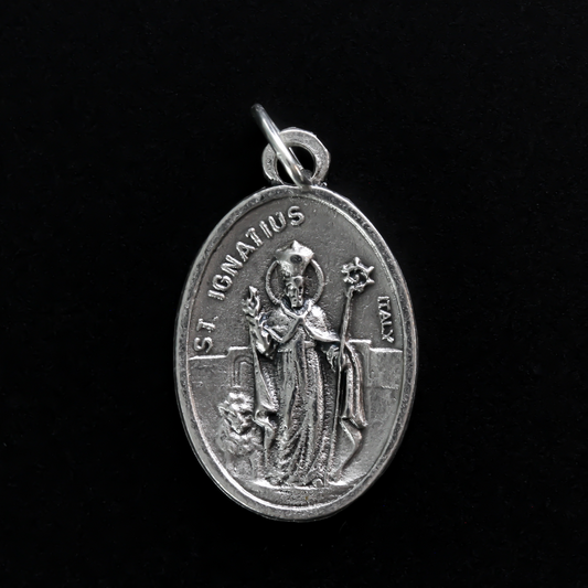 Saint Ignatius of Antioch medal that depicts the saint before a book and cross on the front and "Pray For Us" on the back