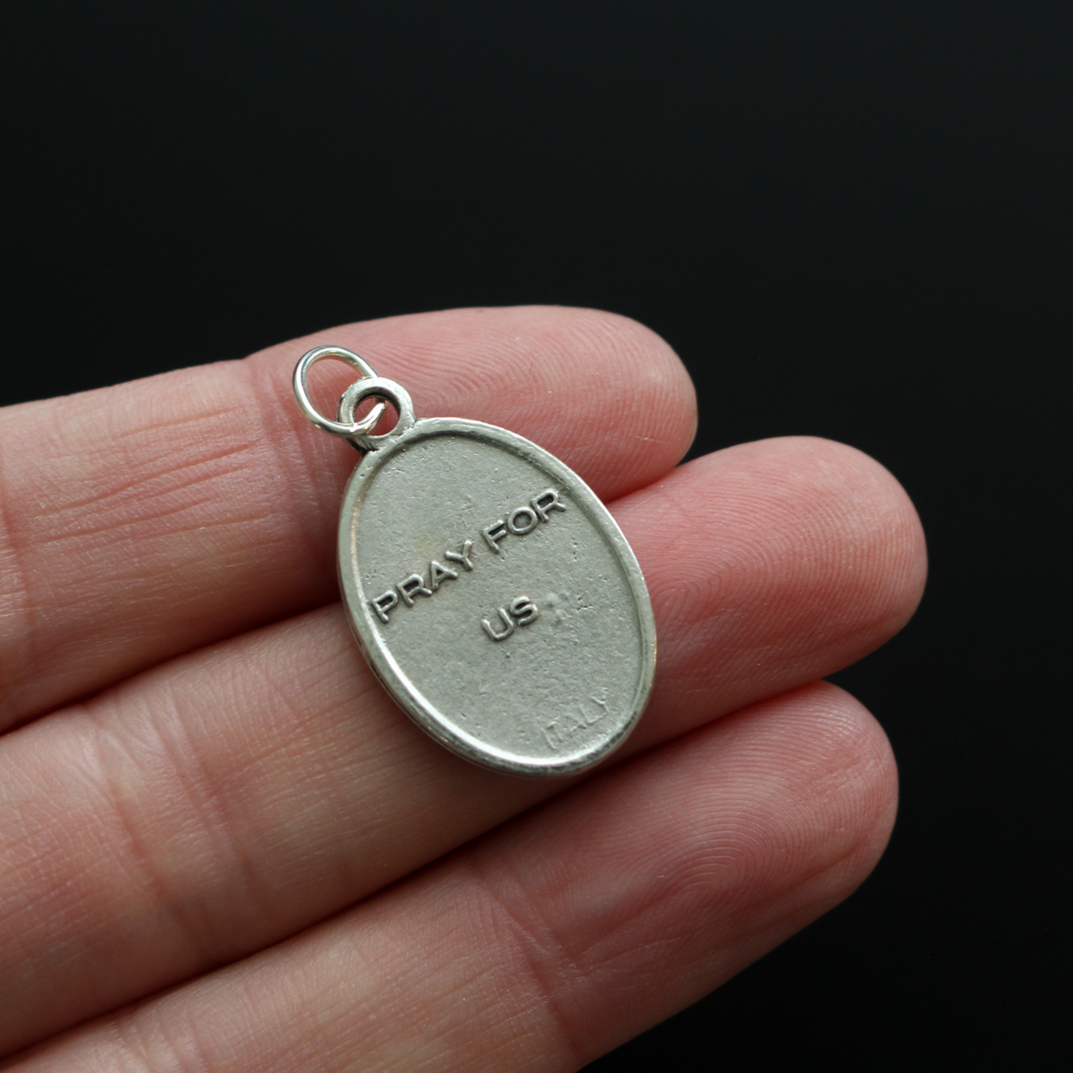 Saint Ignatius of Antioch medal that depicts the saint before a book and cross on the front and "Pray For Us" on the back
