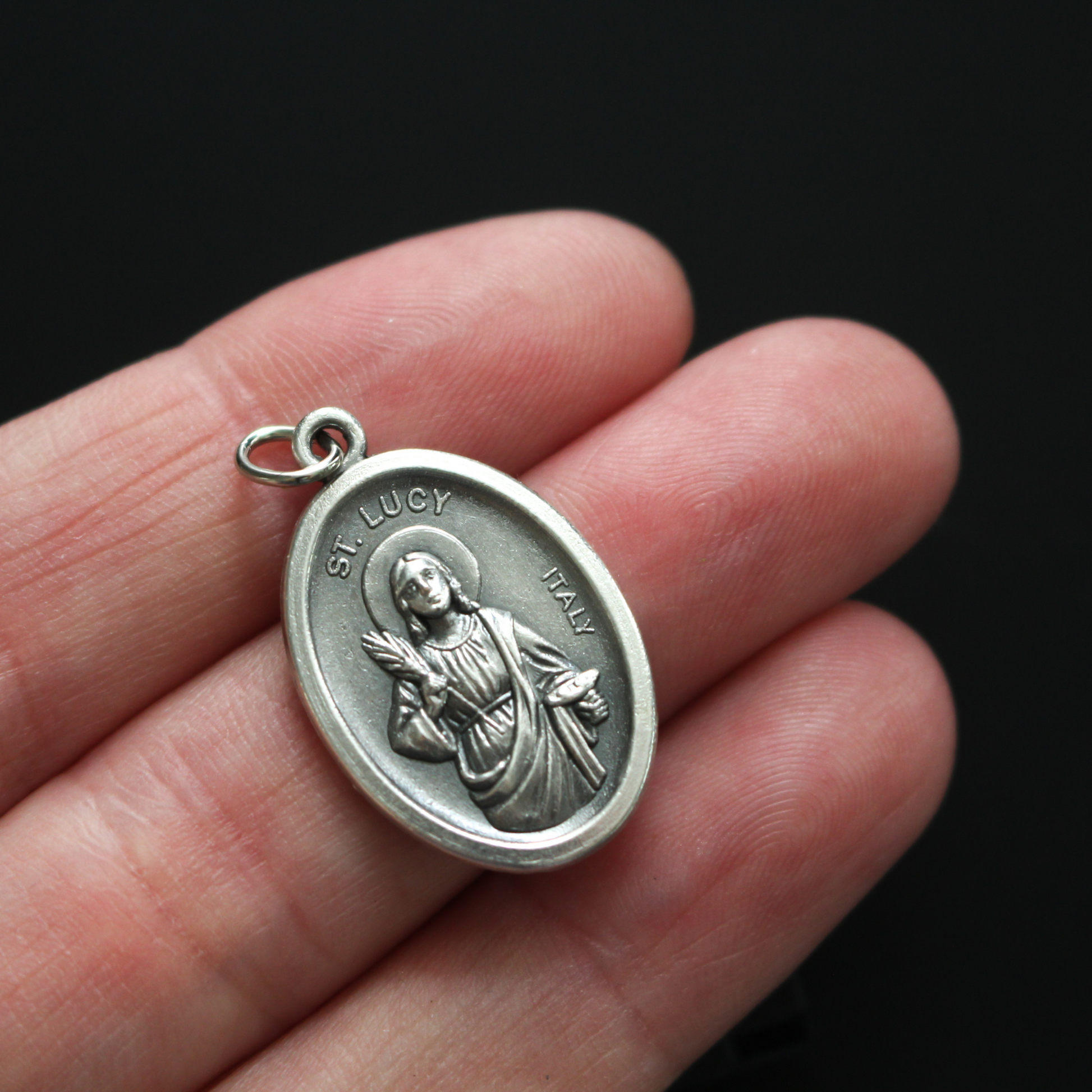 Saint Lucy medal that depicts the saint on the front and "Pray For Us" on the back