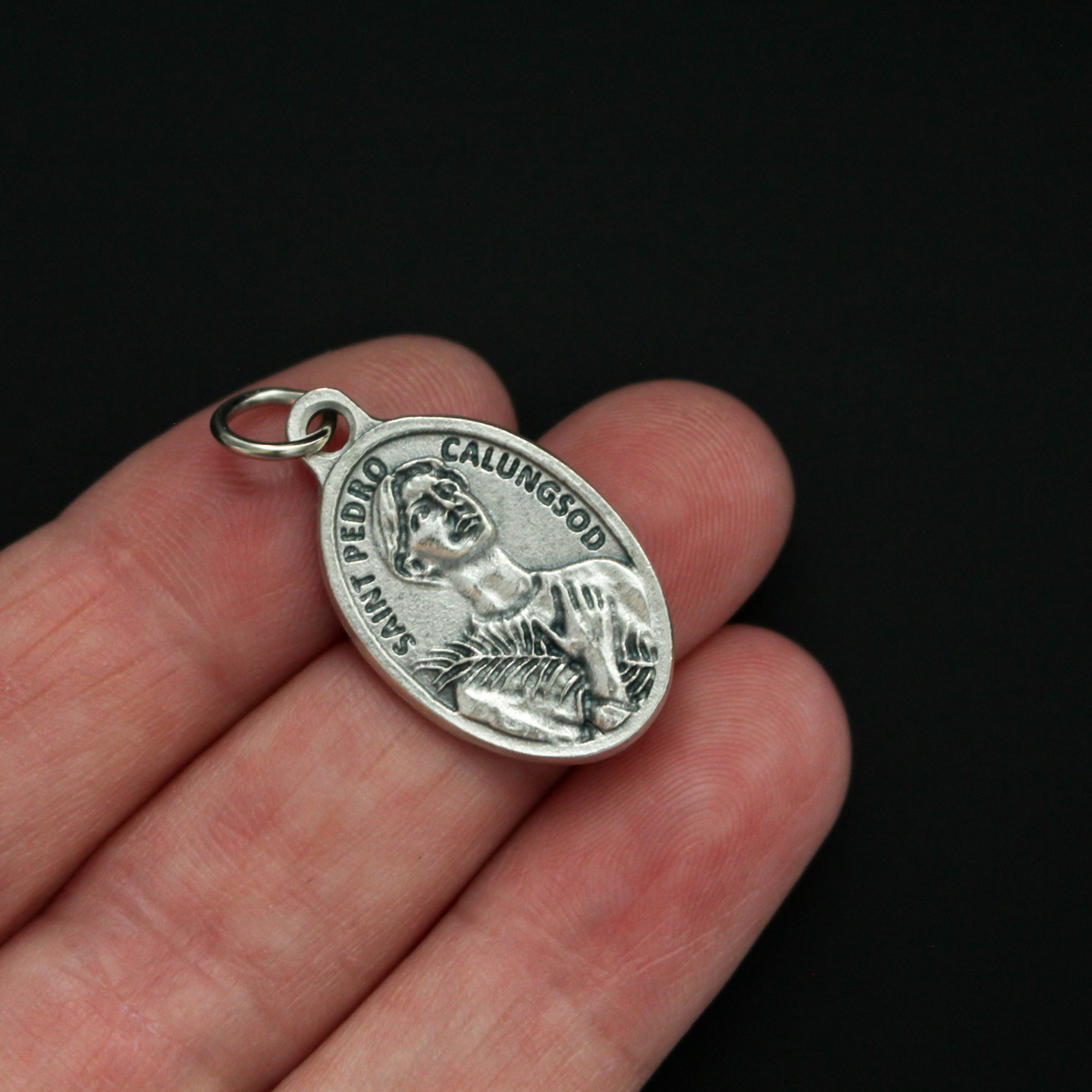 Saint Pedro Calungsod medal that depicts the saint on the front and is marked "Pray For Us" on the back