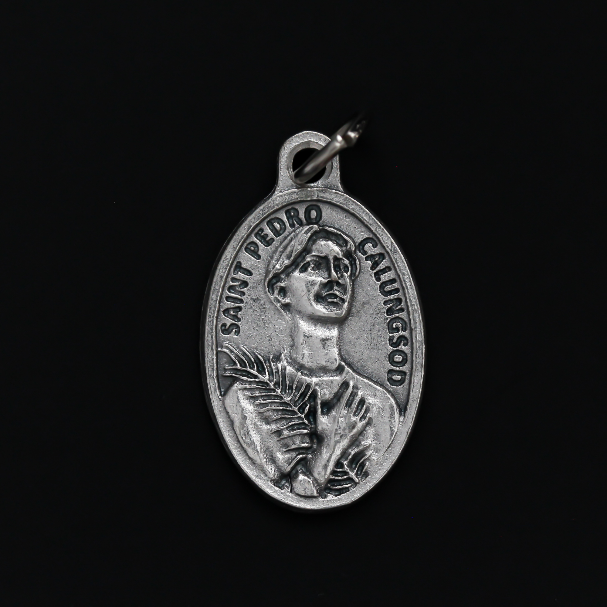 Saint Pedro Calungsod medal that depicts the saint on the front and is marked "Pray For Us" on the back