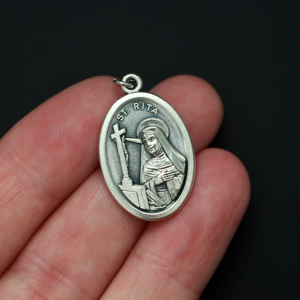 Saint Rita medal that depicts the saint on the front and "Pray For Us" on the back