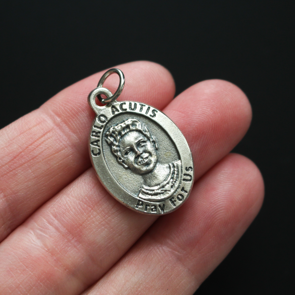Venerable Carlo Acutis medal that depicts the saint on the front and the symbols of the Eucharist on the back