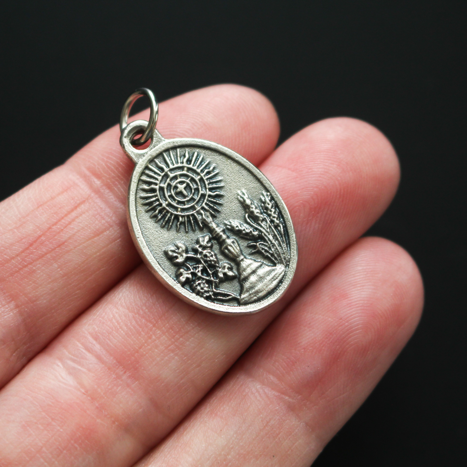 Venerable Carlo Acutis medal that depicts the saint on the front and the symbols of the Eucharist on the back
