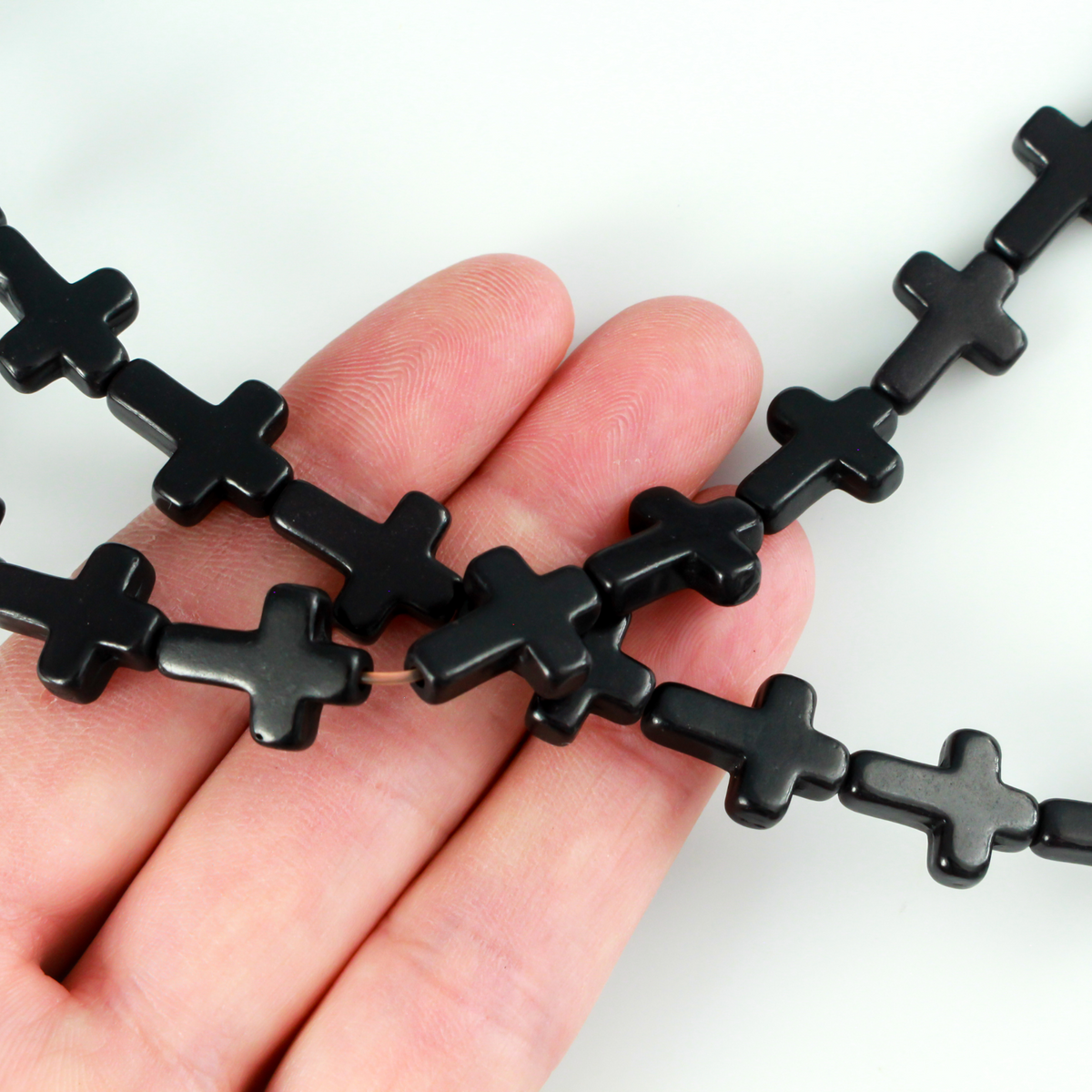 Black cross shaped beads that are a synthetic turquoise material dyed black.