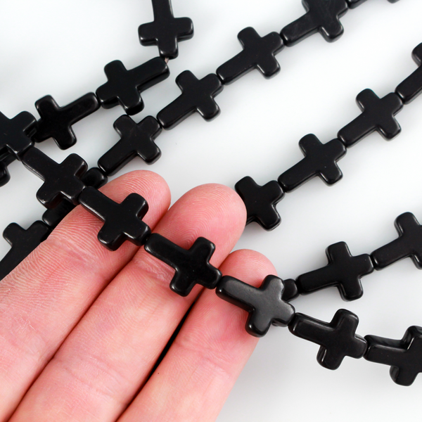 Black cross shaped beads that are a synthetic turquoise material dyed black.