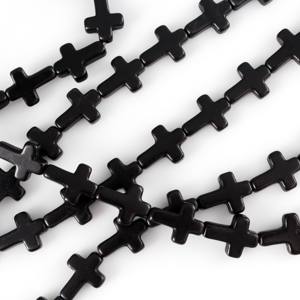 Black cross shaped beads that are a synthetic turquoise material dyed black.