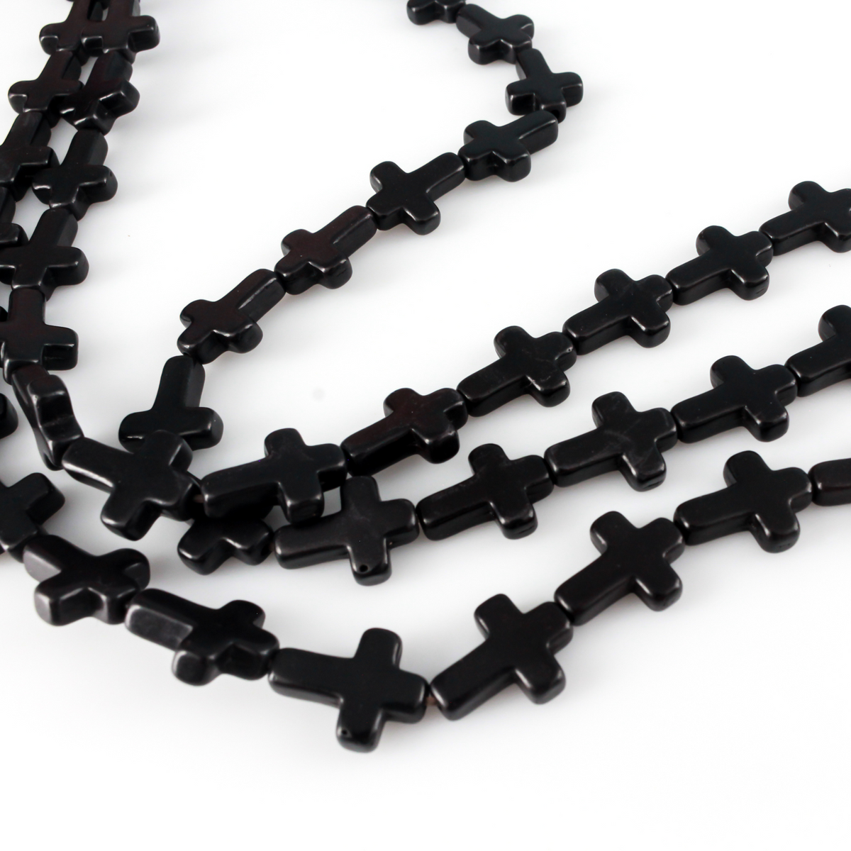 Black cross shaped beads that are a synthetic turquoise material dyed black.