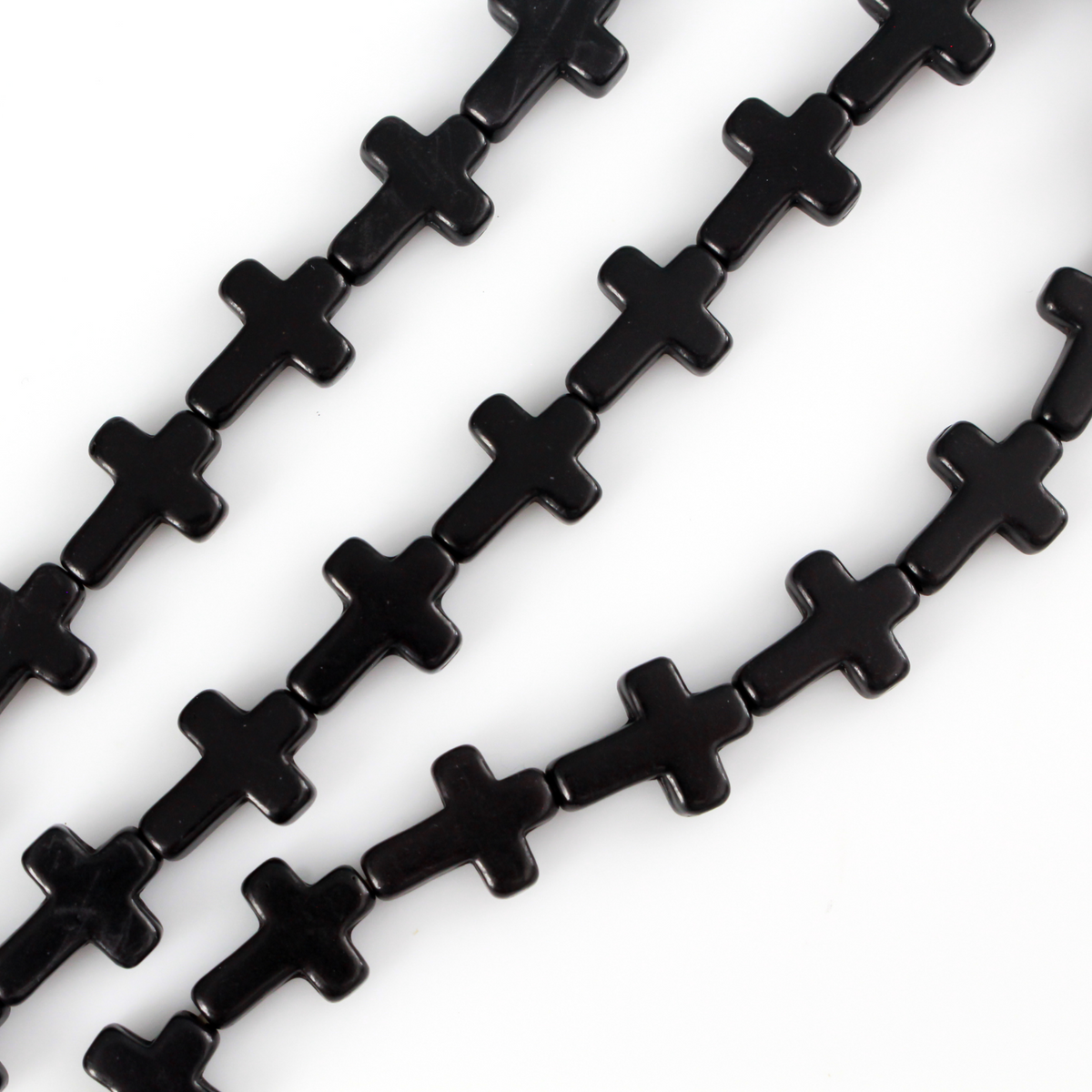 Black cross shaped beads that are a synthetic turquoise material dyed black.