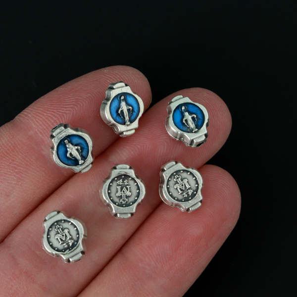 Miraculous Medal oval beads that are silver oxidized base metal made in Italy. The front side of the bead has blue enamel detail, the backside does not