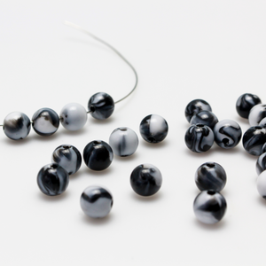 Round black and white marbled opaque beads that are 8mm in diameter with a 1.5mm hole size