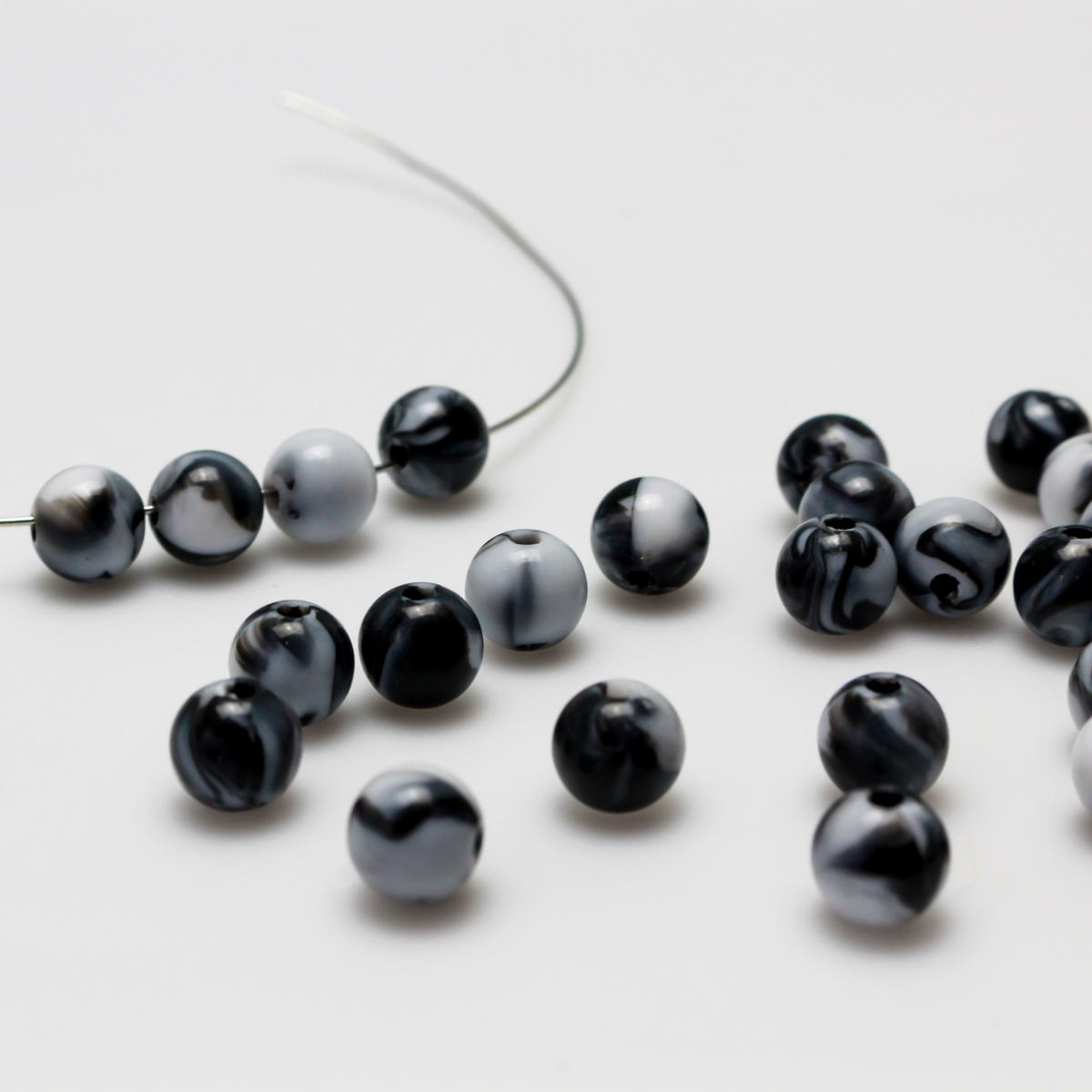 Round black and white marbled opaque beads that are 8mm in diameter with a 1.5mm hole size