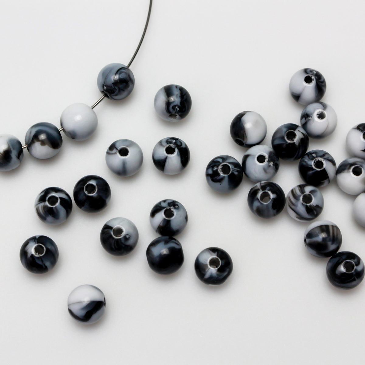 Round black and white marbled opaque beads that are 8mm in diameter with a 1.5mm hole size