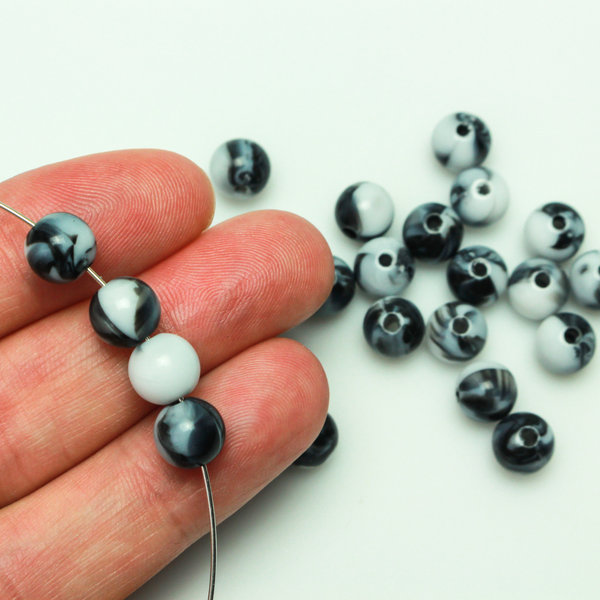 Round black and white marbled opaque beads that are 8mm in diameter with a 1.5mm hole size