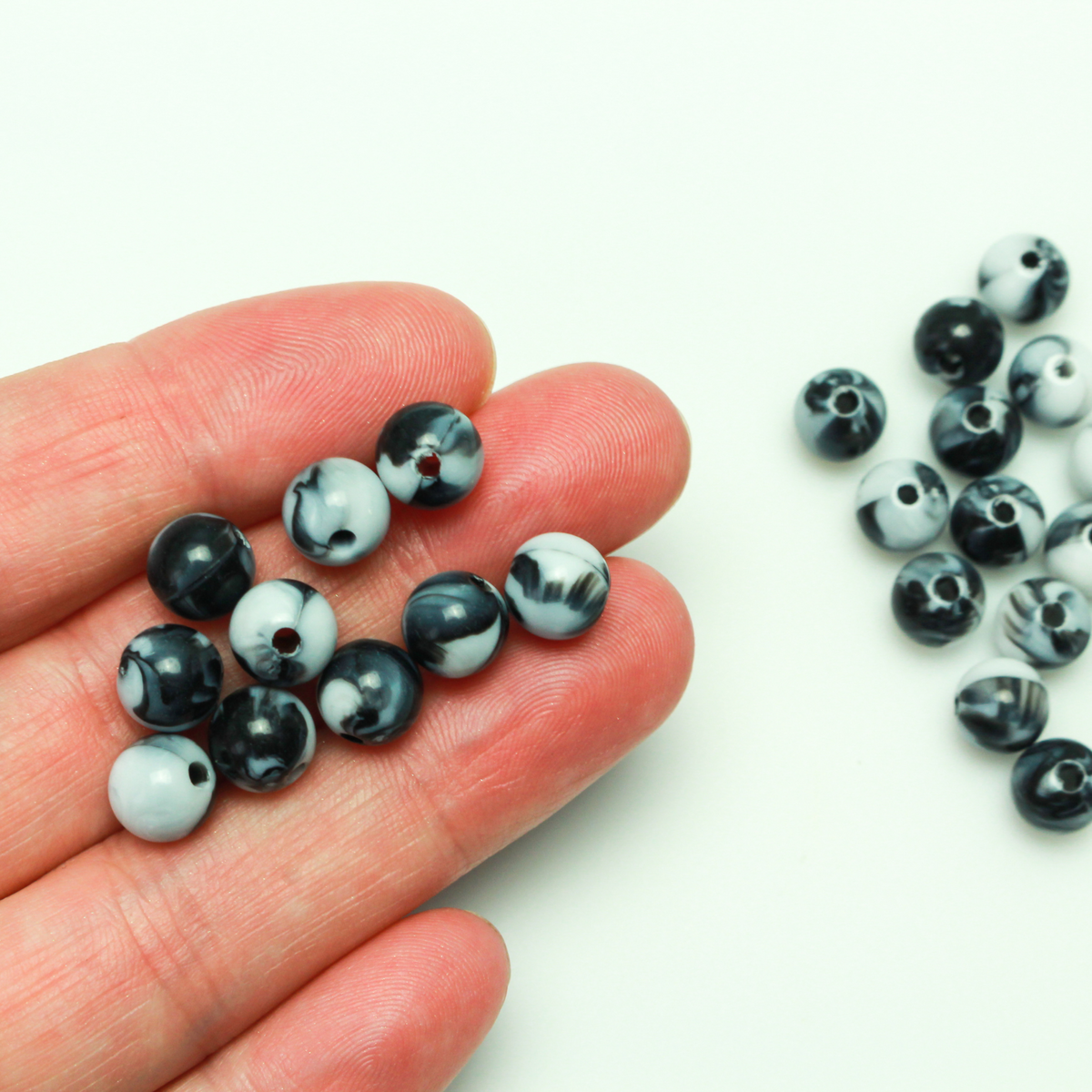 Round black and white marbled opaque beads that are 8mm in diameter with a 1.5mm hole size