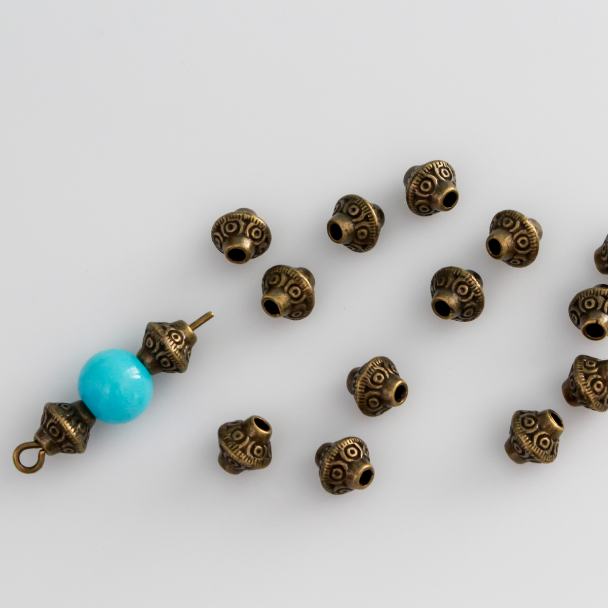 50 metal bicone shaped spacer beads with an antiqued bronze finish and a swirl pattern, 6mm x 6mm