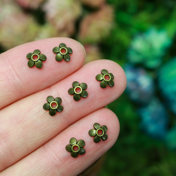 Flower shaped zinc alloy antiqued bronze bead caps that are 6mm in diameter. They can fit beads 6mm - 10mm