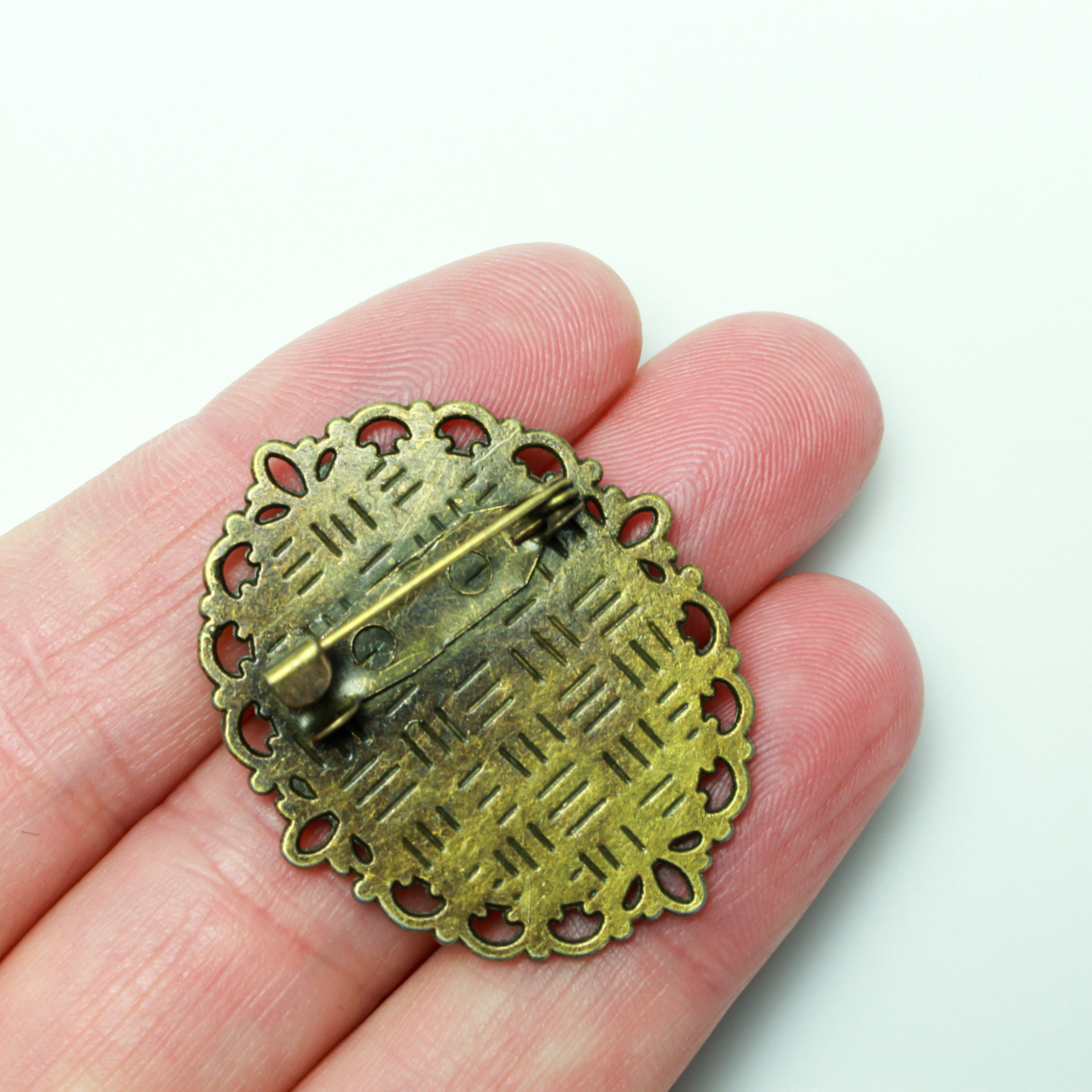 Bronze oval bezel brooch pin with an ornate filigree border. The tray size on this bezel is 25mm x 18mm