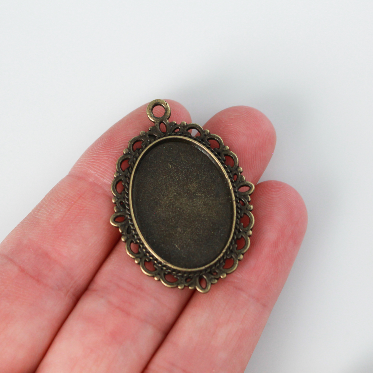 oval pendant cabochon setting in an antiqued bronze color. This is an ornate edge bezel cup with a 25mm x 18mm tray.