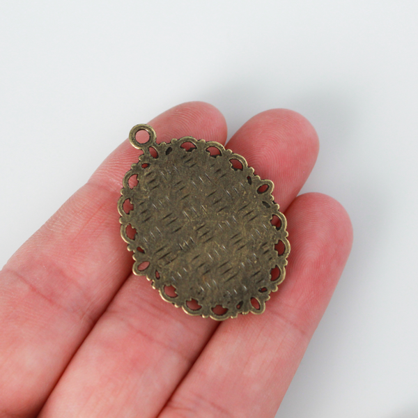 oval pendant cabochon setting in an antiqued bronze color. This is an ornate edge bezel cup with a 25mm x 18mm tray.