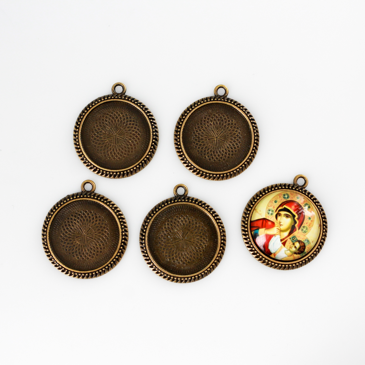 Round pendant cabochon setting in an antiqued bronze color. There is a pattern along the edge of the cup. The tray fits 25mm cabochons