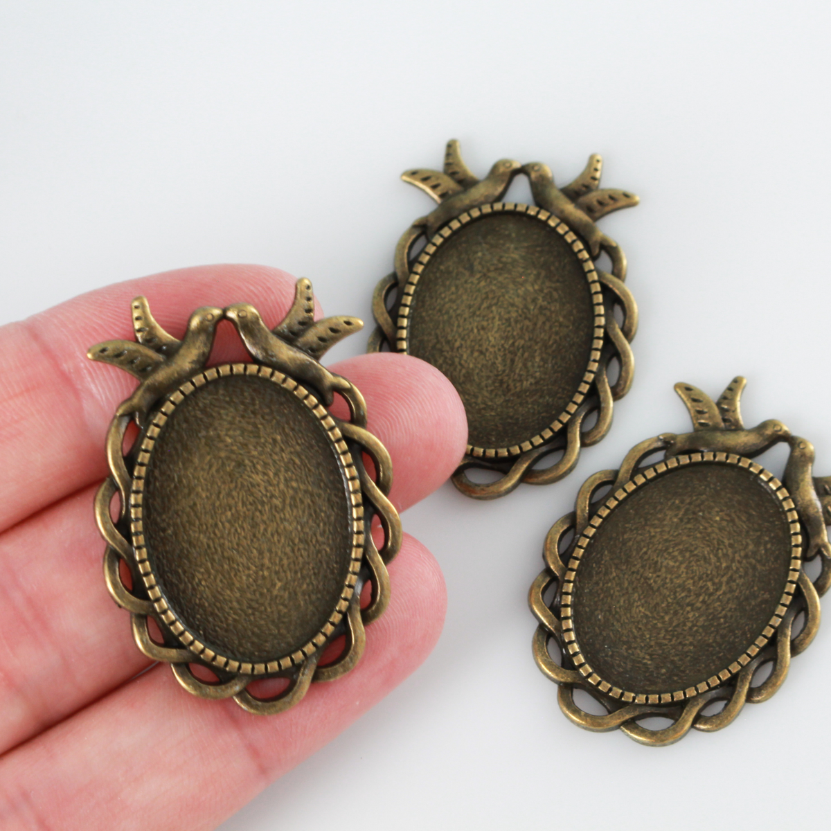 Ornate oval bezel tray setting with an ornate edge and two doves perched at the top