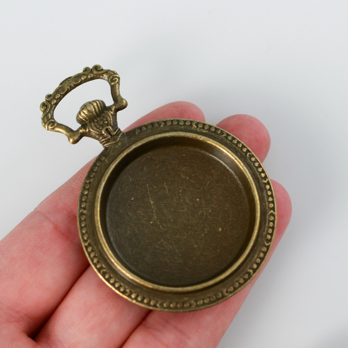 Large bronze cabochon setting shaped like an old ornate pocket watch with a 33mm tray.