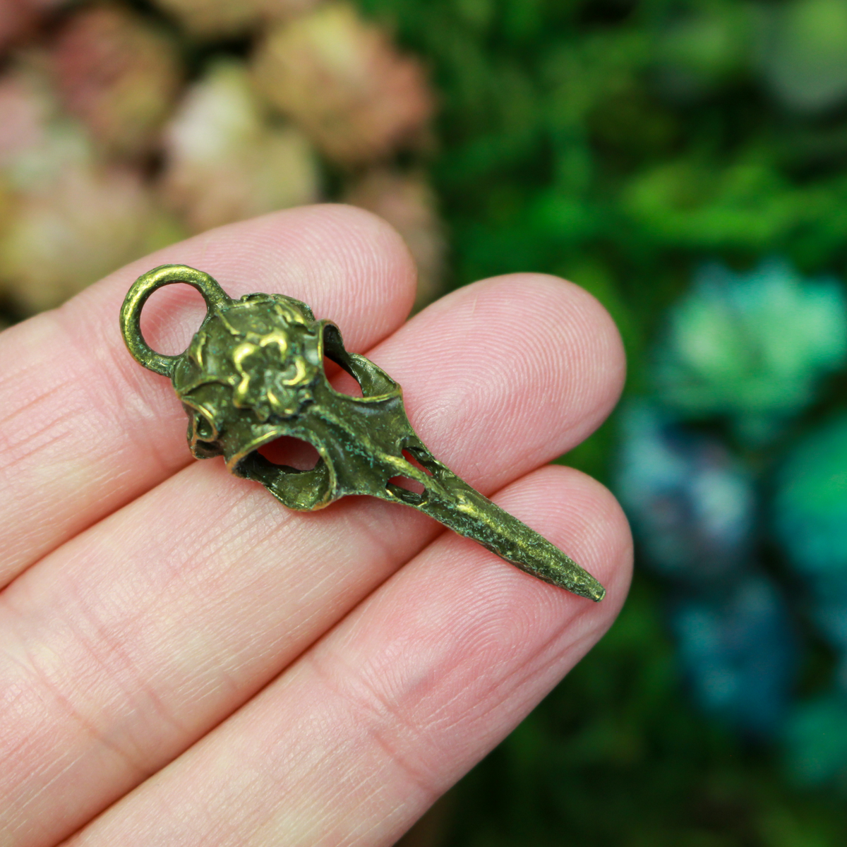 Antiqued bronze tone raven skull charms that have a flower design on the top