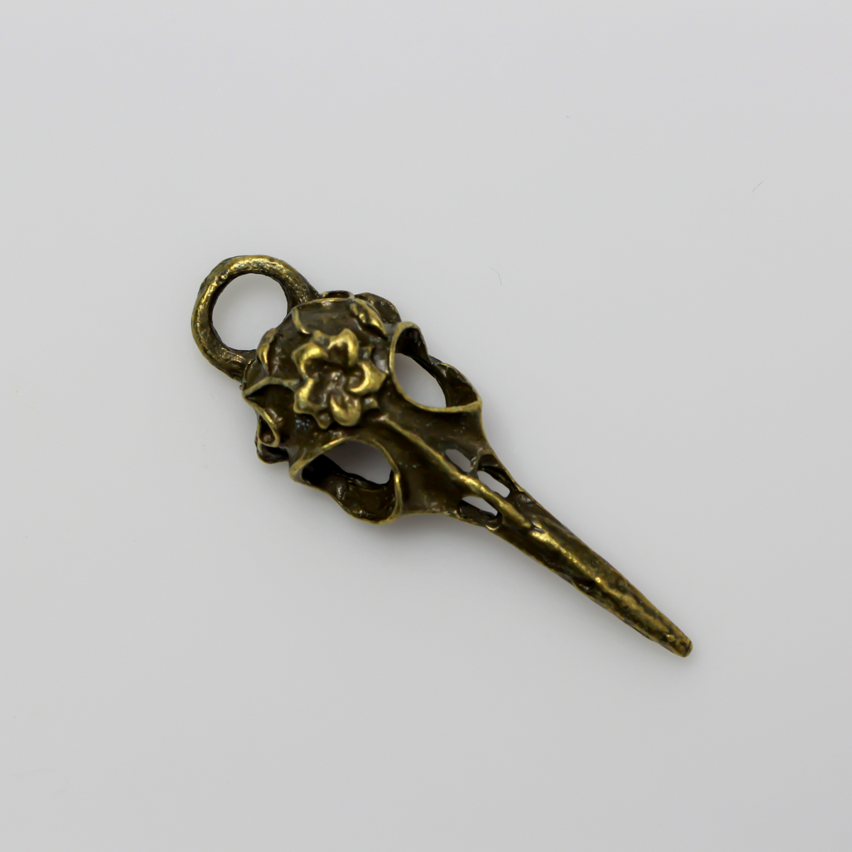 Antiqued bronze tone raven skull charms that have a flower design on the top