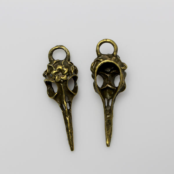 Antiqued bronze tone raven skull charms that have a flower design on the top