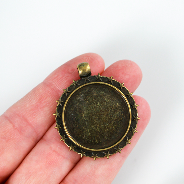 Round pendant cabochon setting in an antiqued bronze color. This bezel setting has 5 point stars along the edge. The tray fits 25mm cabochons.
