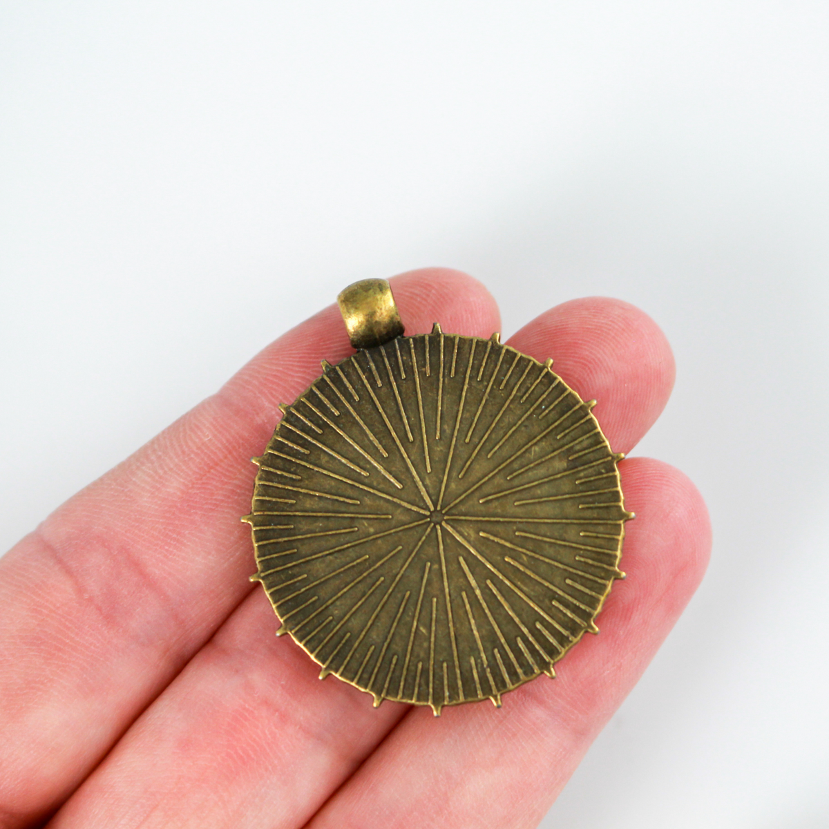 Round pendant cabochon setting in an antiqued bronze color. This bezel setting has 5 point stars along the edge. The tray fits 25mm cabochons.