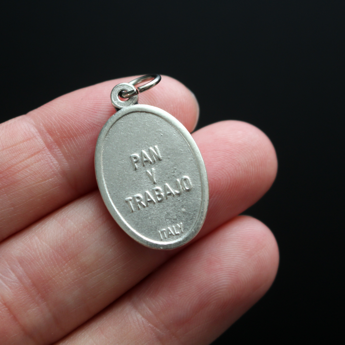 St. Cajetan (Cayetano) oval medal that depicts the saint on the front and "Pan Y Trabajo" on the back which translates from Spanish to "Bread and Labor"