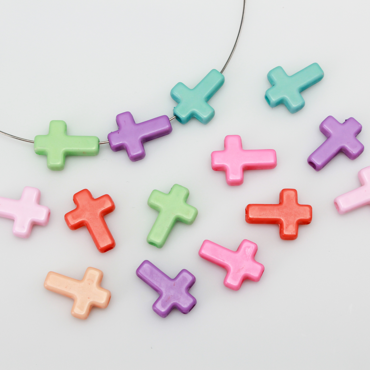 Cross shaped opaque acrylic beads in a random mix of pastel colors.