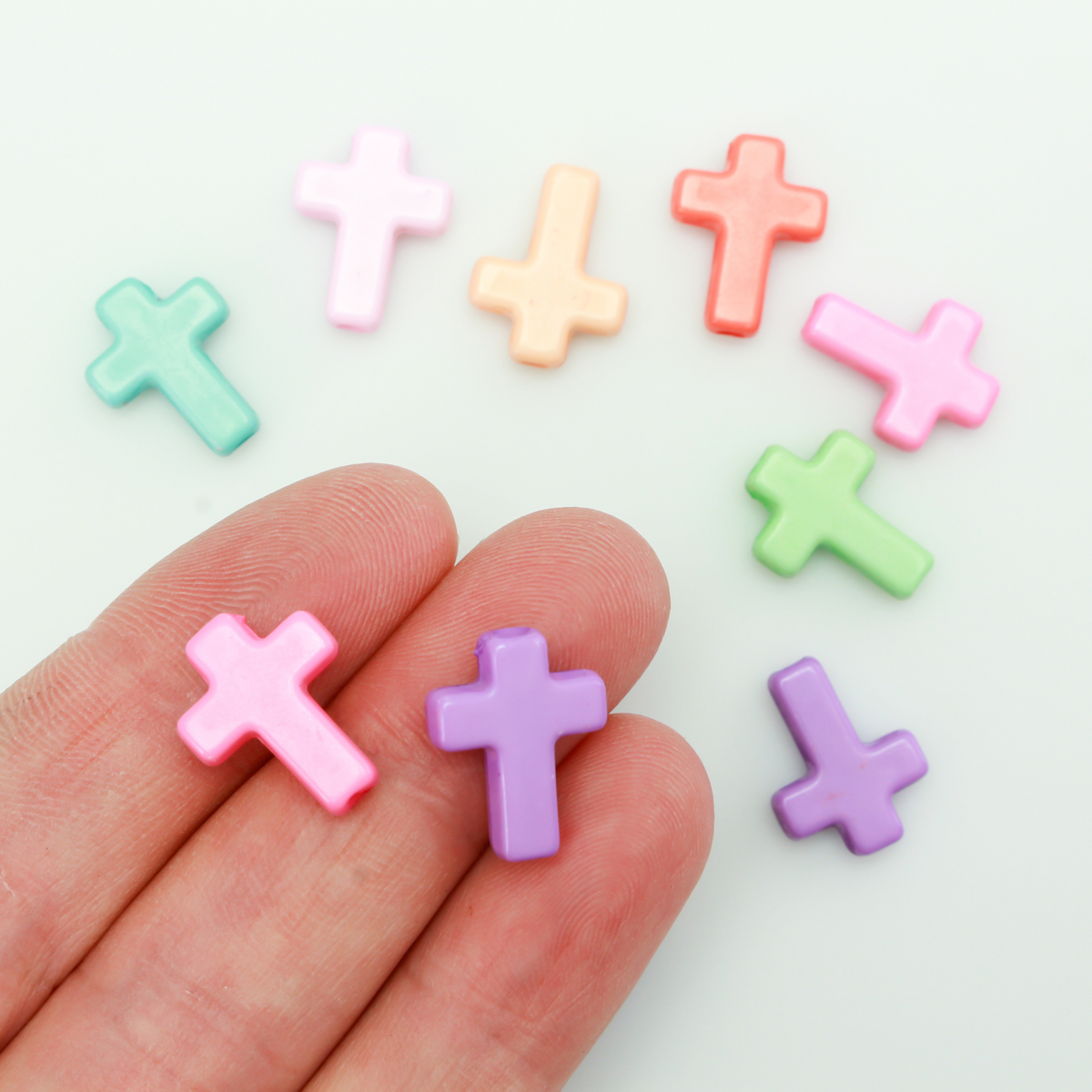 Cross shaped opaque acrylic beads in a random mix of pastel colors.