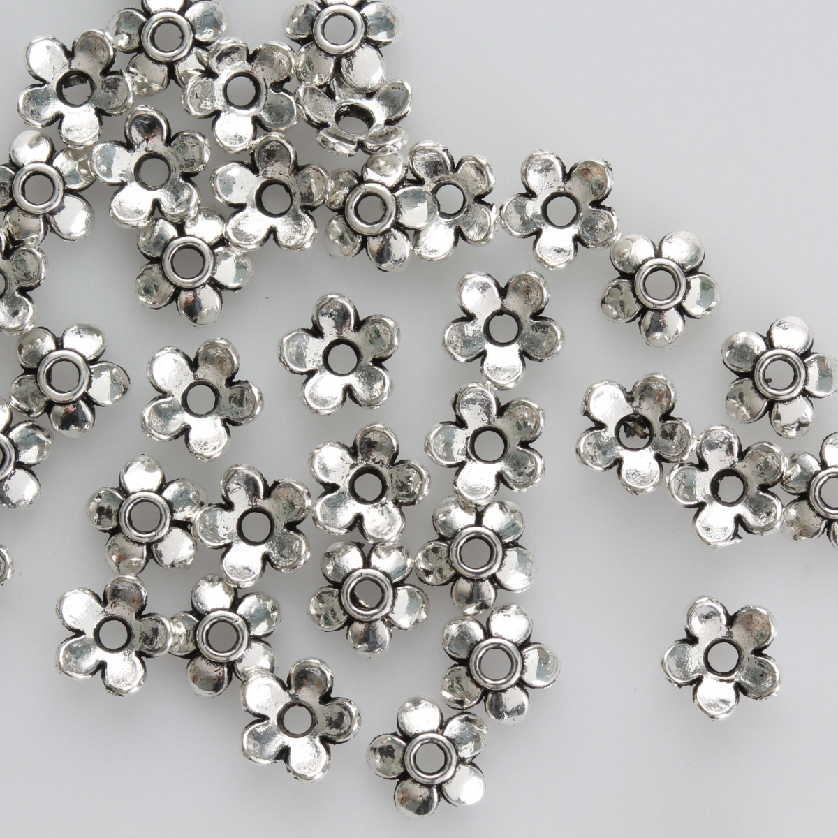 Flower shaped zinc alloy antiqued silver bead caps that are 6mm in diameter