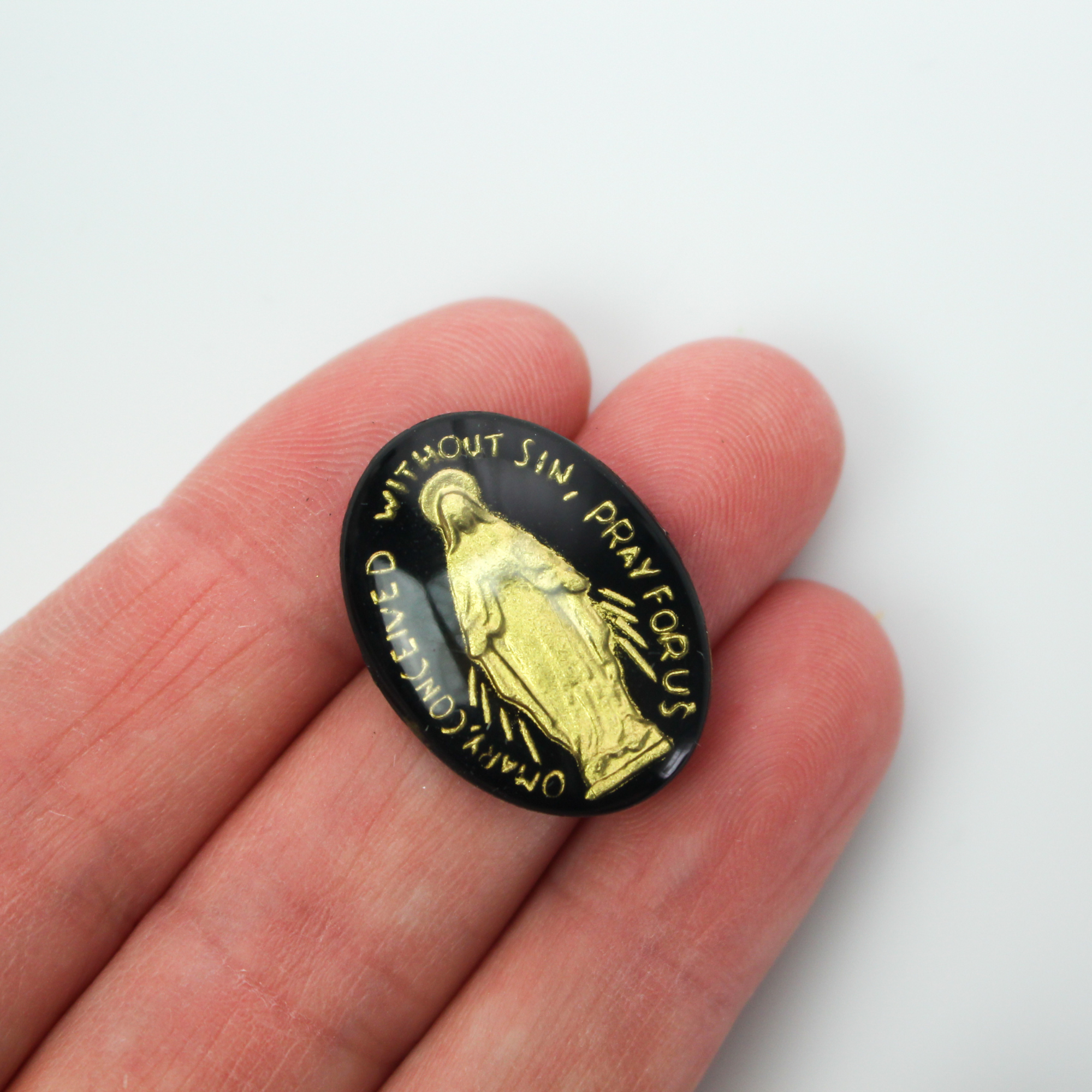 Glass cabochon of the Miraculous medal in a gold and black design. Hand pressed and painted in the Czech Republic