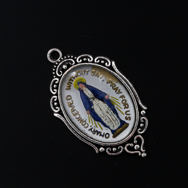 Glass cabochon of the Miraculous medal in a blue and silver design. Hand pressed and painted in the Czech Republi