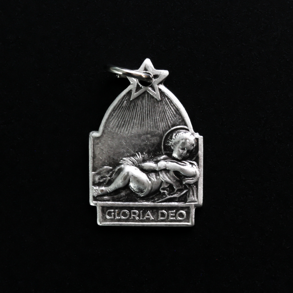 Antique reproduction nativity charm that depicts Jesus in the manger, the bail that holds the jump ring is star-shaped to represent the Star of Bethlehem