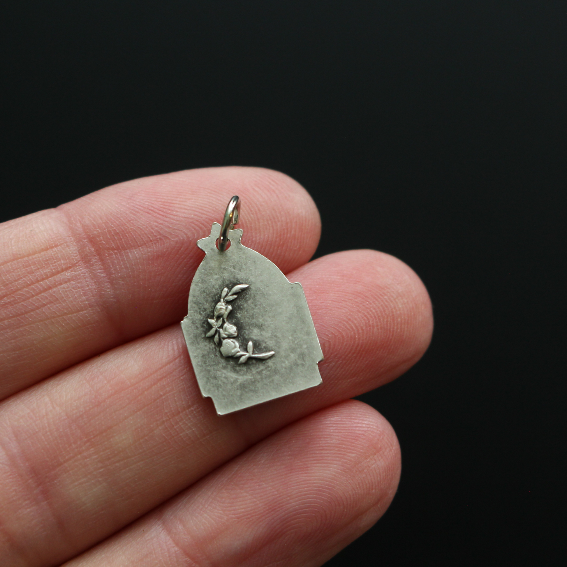 Antique reproduction nativity charm that depicts Jesus in the manger, the bail that holds the jump ring is star-shaped to represent the Star of Bethlehem