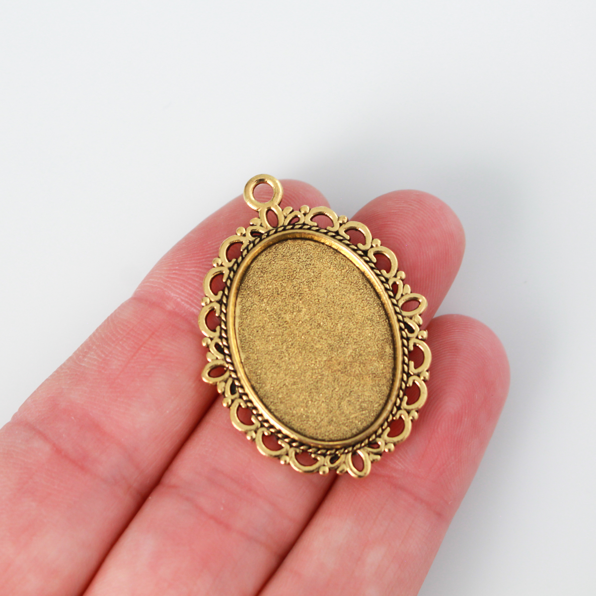 oval pendant cabochon setting in an antiqued gold color. This is an ornate edge bezel cup with a 25mm x 18mm tray.