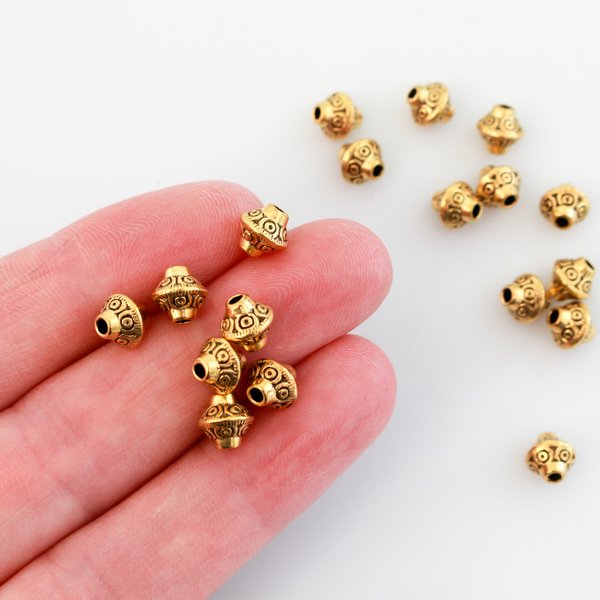 50 metal bicone shaped spacer beads with an antiqued golden finish and a carved dot design