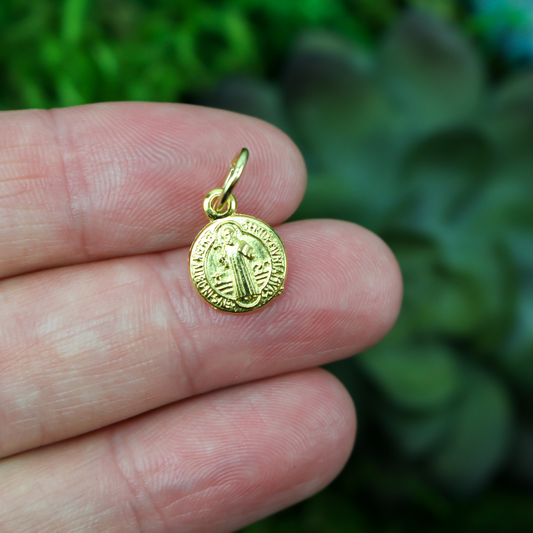 tiny round saint benedict medal that is gold tone in color 3/8" diameter