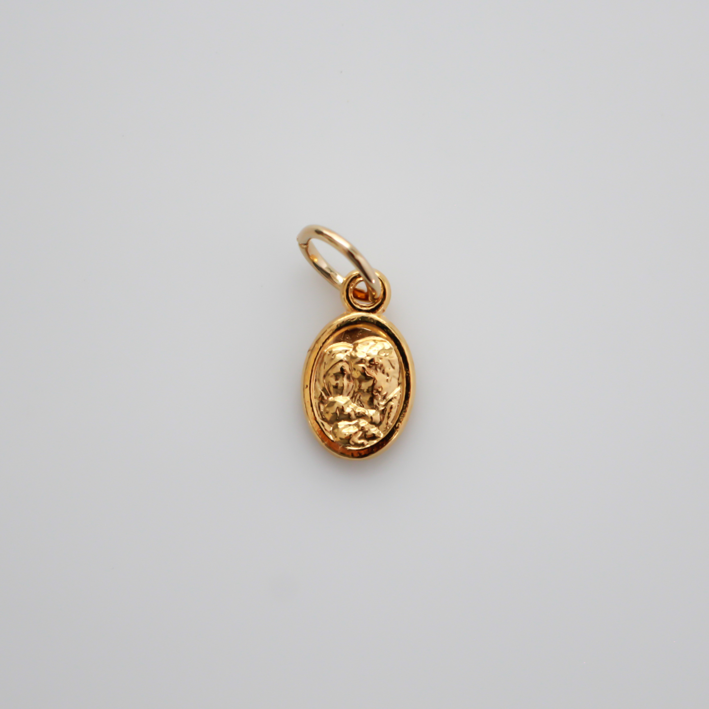 Gold tone mini medal that depicts Saint Joseph holding the child Jesus on one side and the Holy Family depicted on the other side, 1/2" long