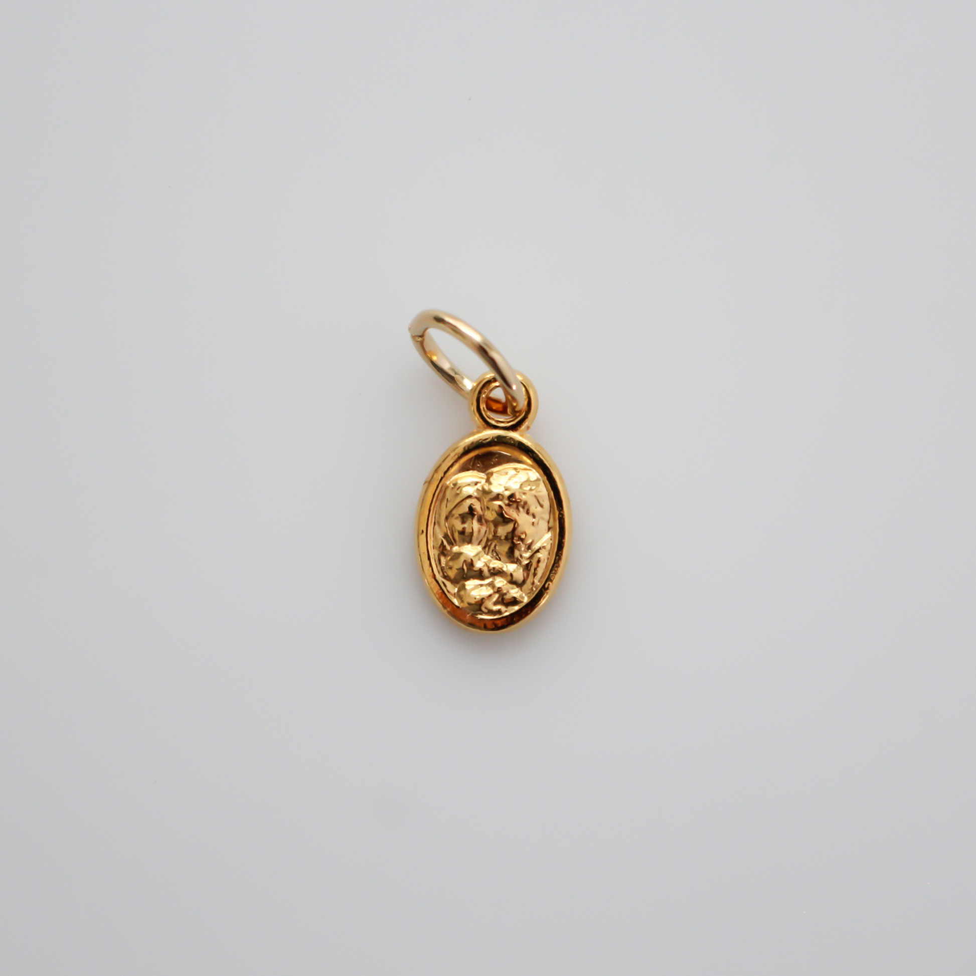 Gold tone mini medal that depicts Saint Joseph holding the child Jesus on one side and the Holy Family depicted on the other side, 1/2" long