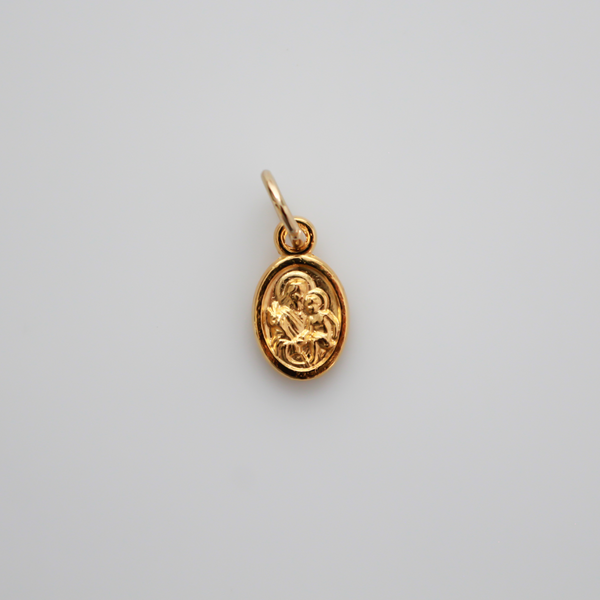 Gold tone mini medal that depicts Saint Joseph holding the child Jesus on one side and the Holy Family depicted on the other side, 1/2" long