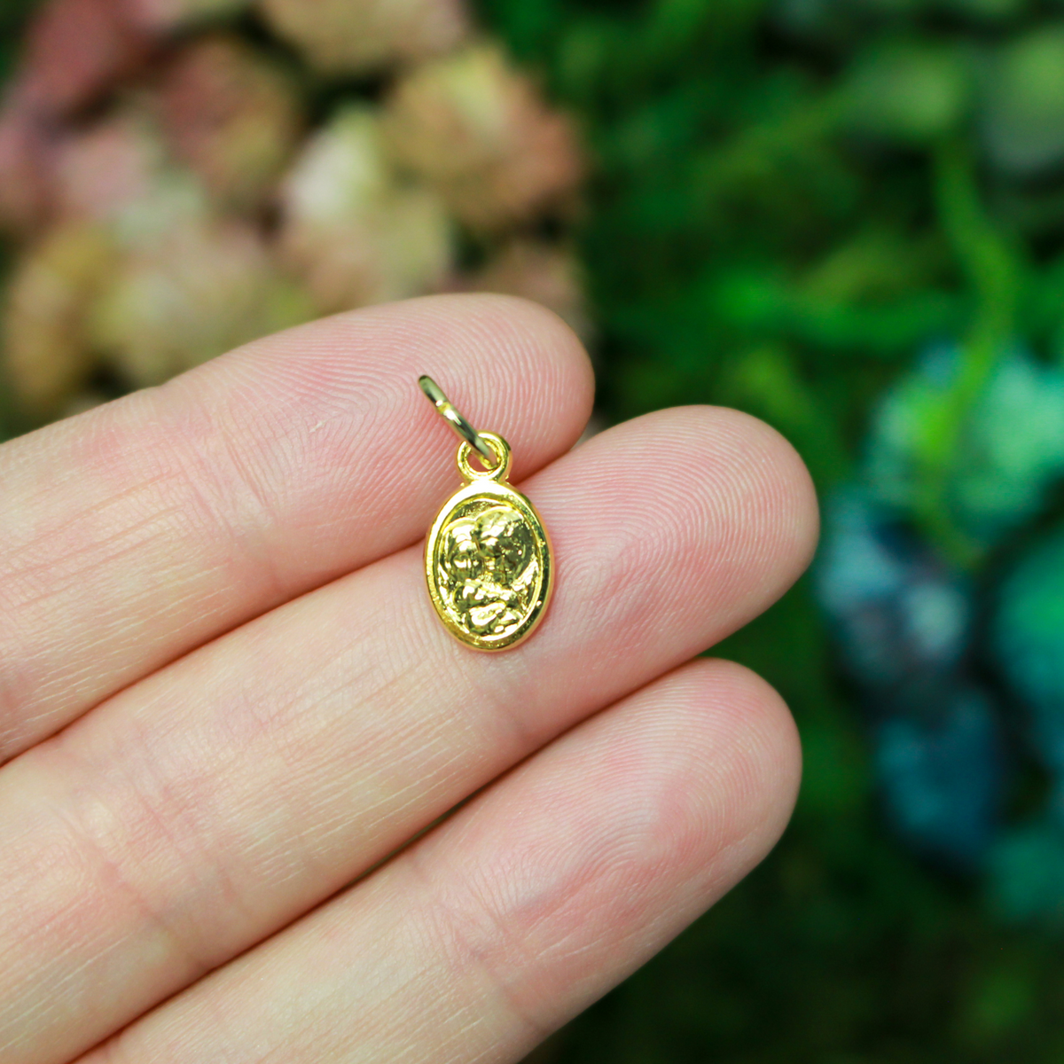 Gold tone mini medal that depicts Saint Joseph holding the child Jesus on one side and the Holy Family depicted on the other side, 1/2" long